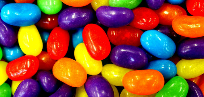 Different shades of red, blue, yellow, orange, and purple jellybeans lay in a pile.