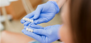 A dentist's gloved hands each hold a set of dental veneers.