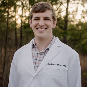 Dr. Joshua Ludford, newly welcomed to Arkansas Family Dental, smiles broadly in his dental coat.
