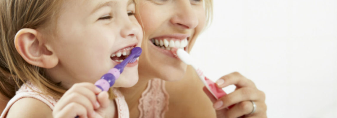 A mother and her toddler daughter practice dental care for children together.