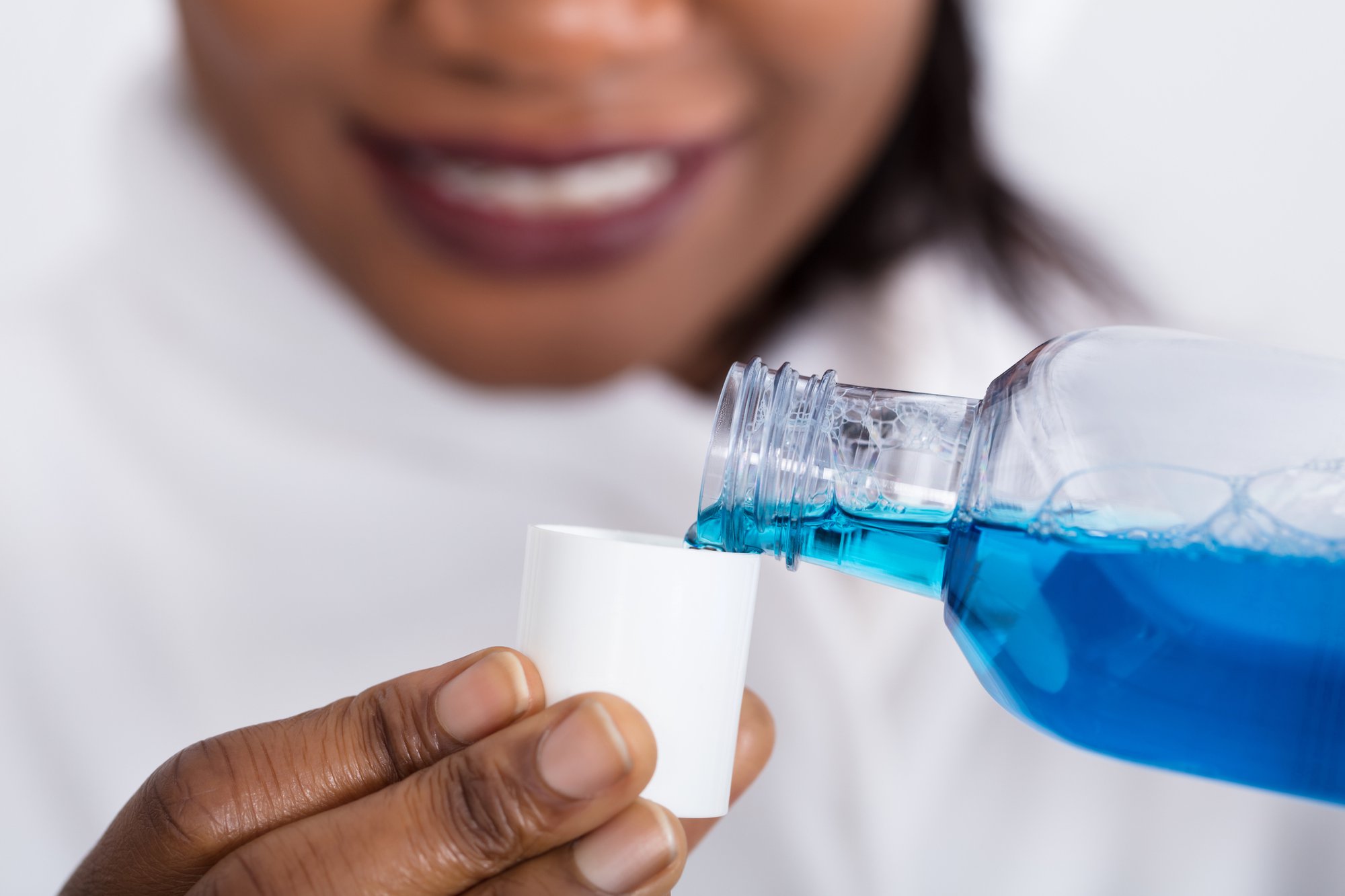 lady pouring blue mouthwash into the cap