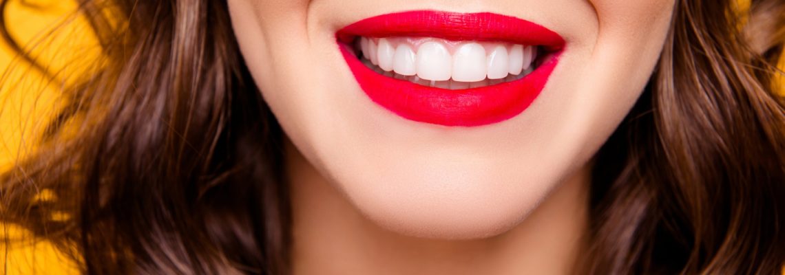 Close up half face portrait of toothy woman with beaming smile red lips white straight healthy teeth